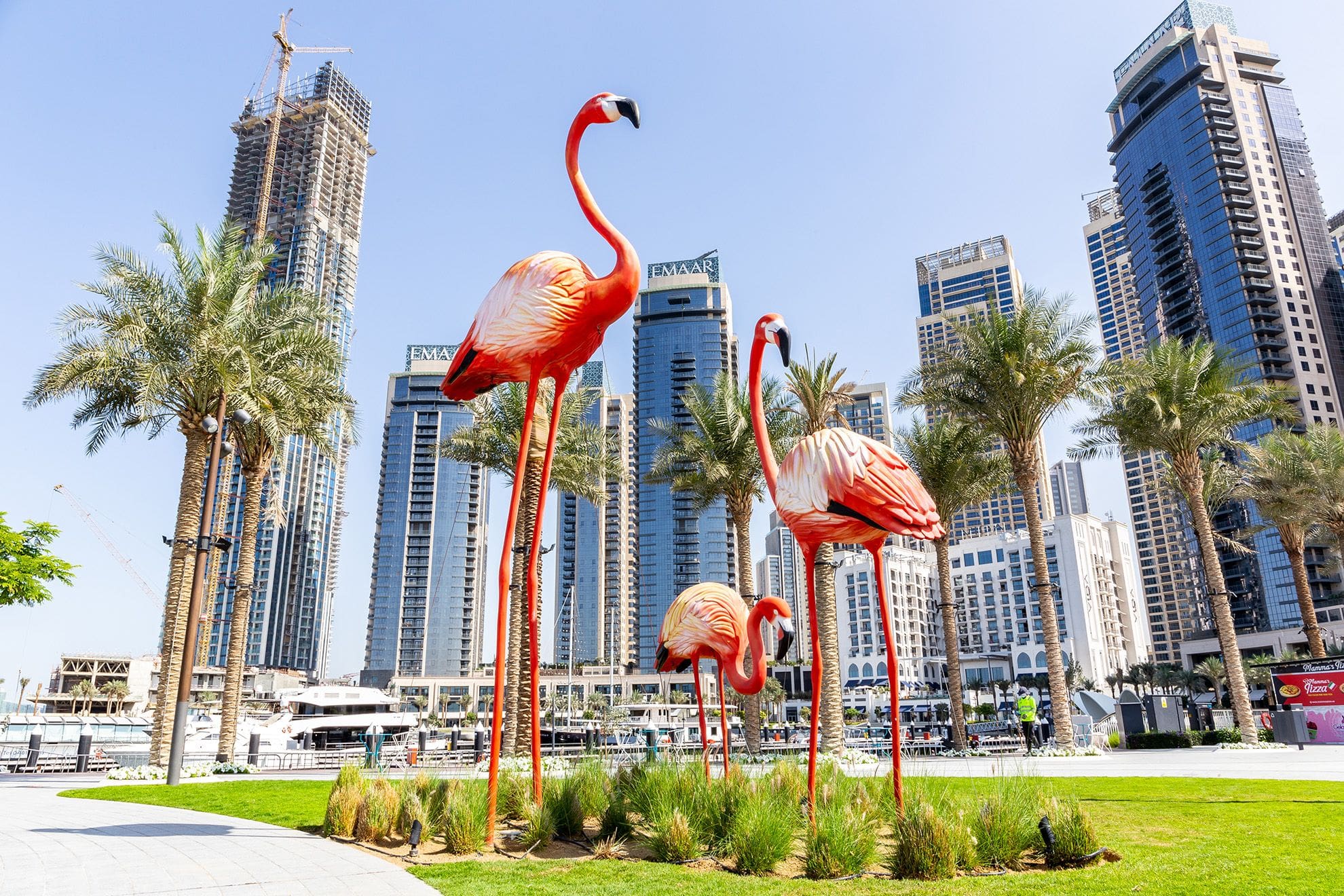 Big flamingos statues on Dubai Creek Harbour promenade with skyline in the background