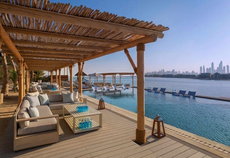 pergolas with outdoor sofas next to a pool