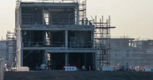 Close-up of Palm Jebel Ali villa structural frame with construction workers on upper floors