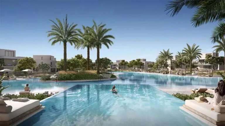 infinity pool overlooking a lake with beach in the oasis by emaar